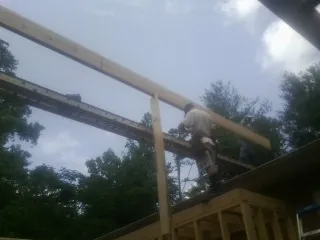 Carpenter setting a ridge beam over a new addition frame — Ice Dam Removal by Roofing Brothers in Litchville
