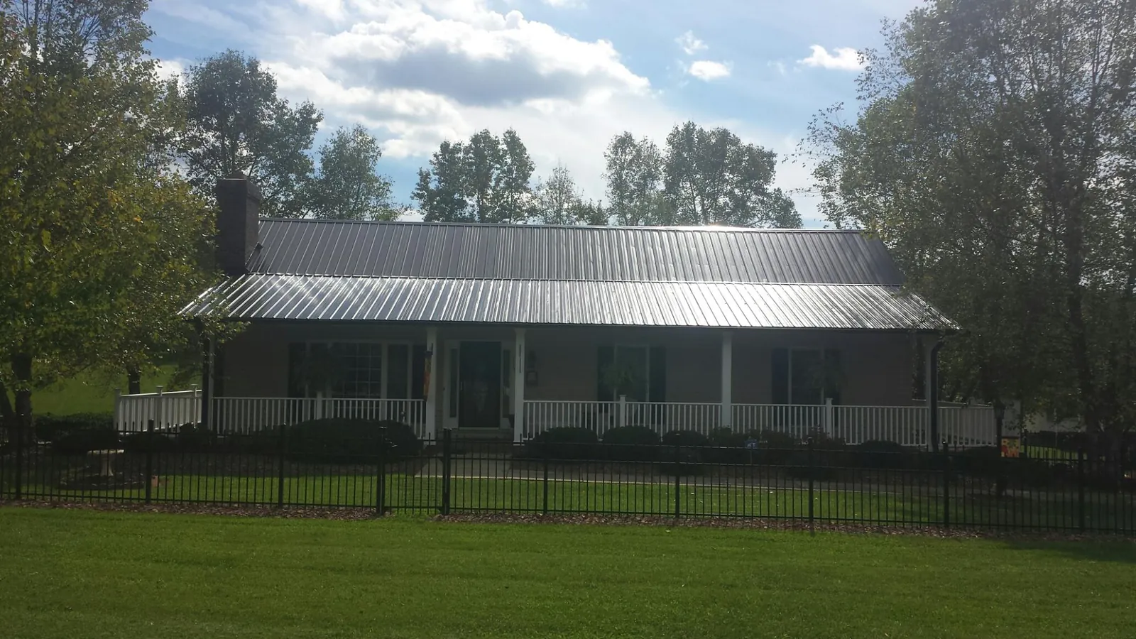 Gray metal roof on a brick ranch with a full width front porch — Gutter Guard Installation work by our crew in Litchville
