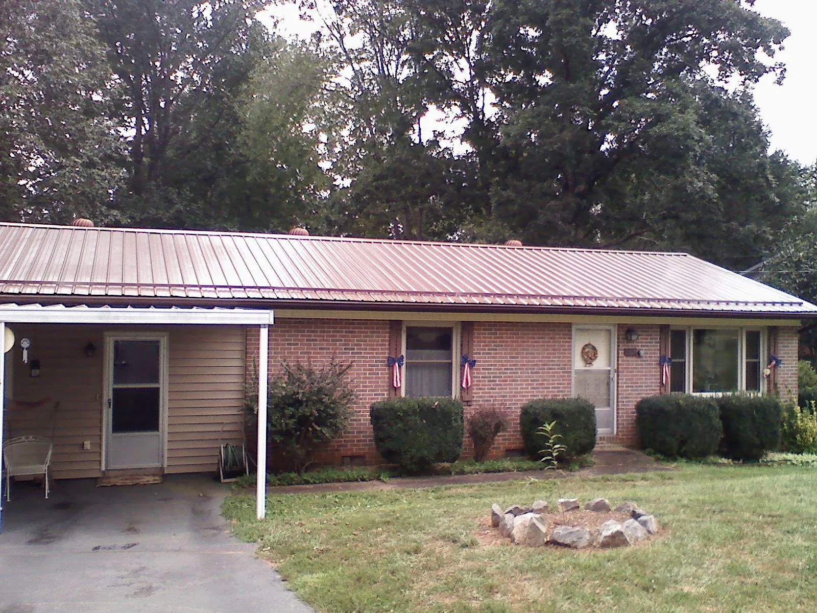Bronze metal roof and carport on a brick ranch home — Roof Repair work by our crew in Litchville