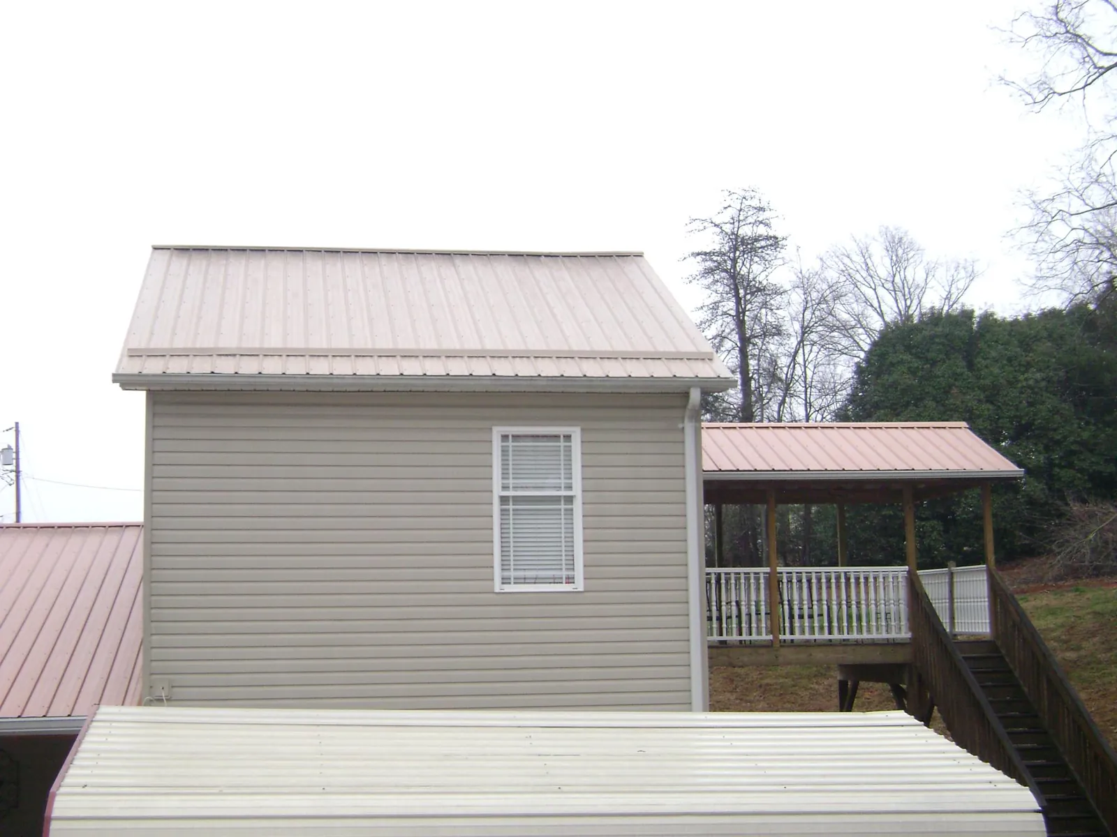 Tan metal roofs on a two story addition and attached porch, from a Roof Replacement job in Litchville