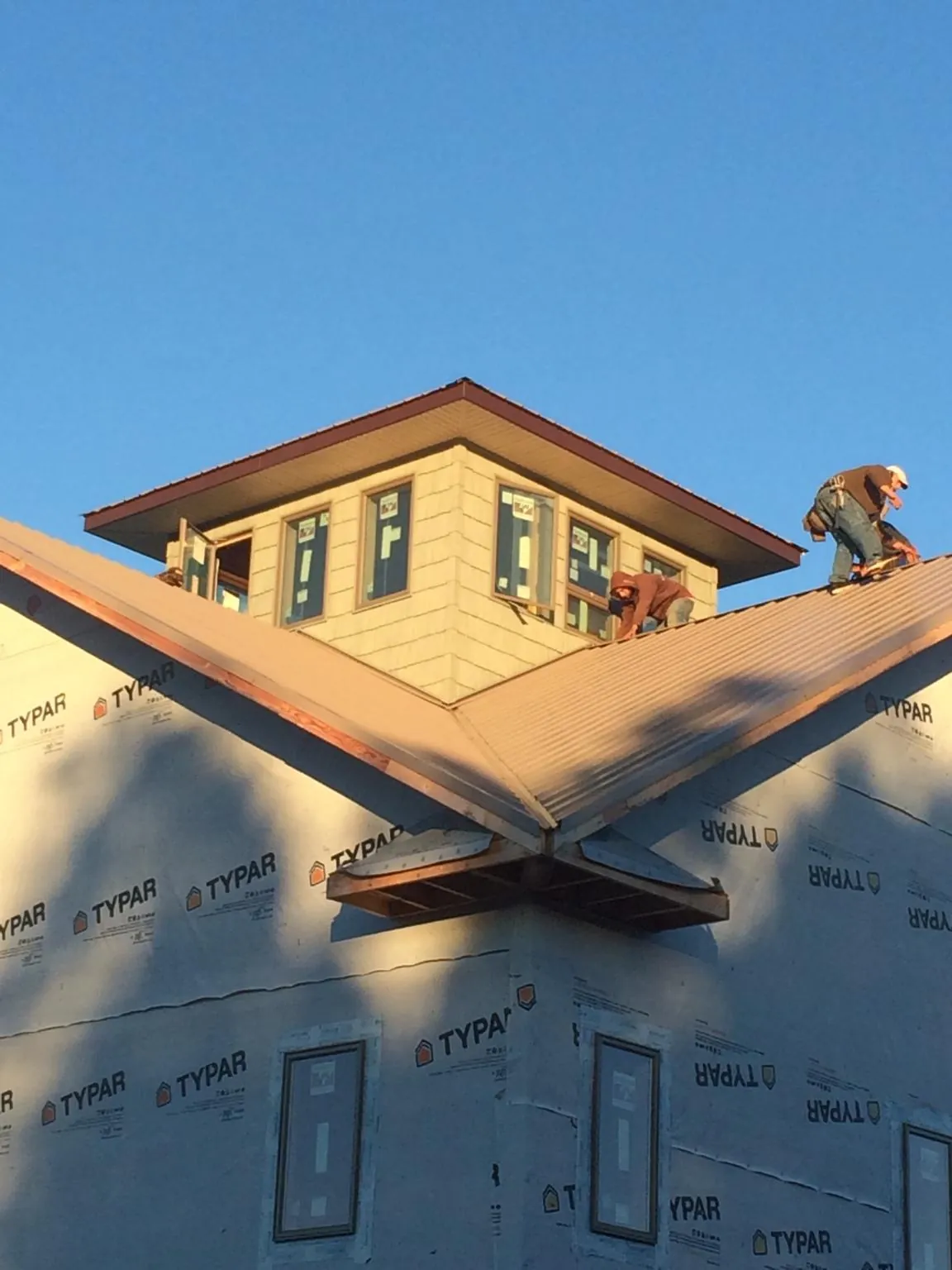 Roofers working around a rooftop cupola on a new metal roof at sunset — Roof Waterproofing in Litchville by Roofing Brothers